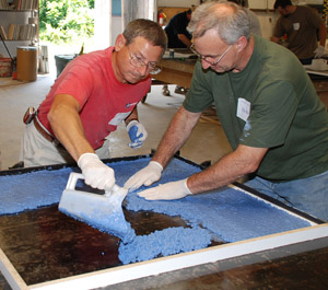 two men pouring blue concrete into mold