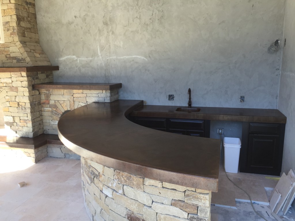 outdoor kitchen with brown curved concrete countertop and stacked stone