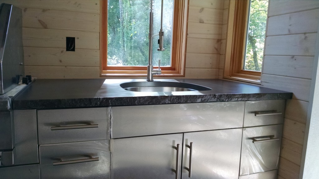black concrete countertop with stone edge in outdoor kitchen with stainless steel cabinets