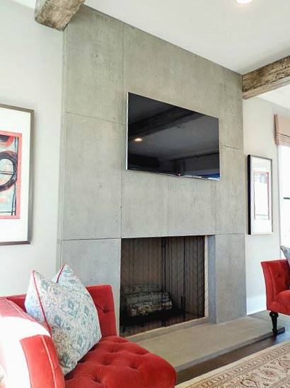 full height concrete fireplace surround in living room with timber beams and red chairs