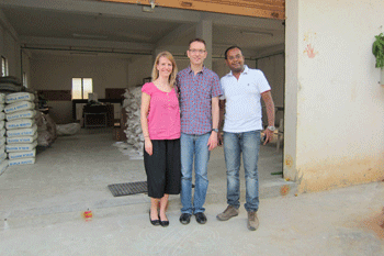 three people standing in front of concrete block shop with bags of cement