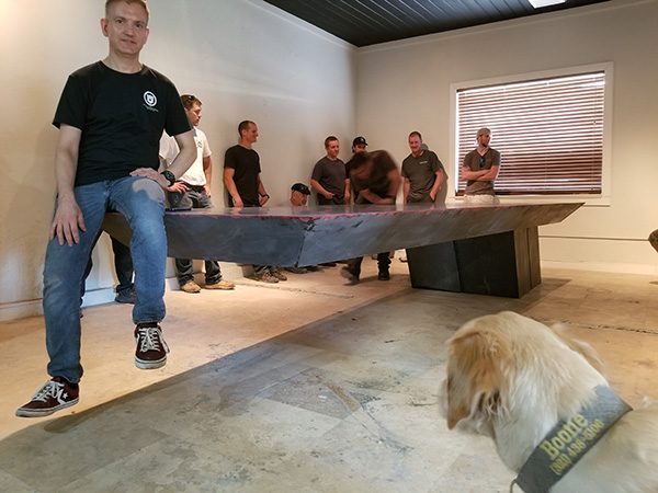 Jeff Girard sitting on edge of 11 foot cantilevered concrete table